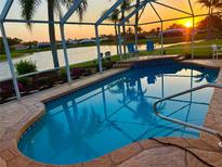 Screened-in pool features a ledge with chairs overlooking the beautiful lake during a colorful sunset at 1727 Waxwing Cir, Venice, FL 34293