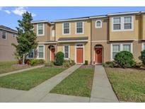 Well-manicured townhome exteriors feature landscaping, sidewalks, and tan and yellow facades under a sunny sky at 7024 Timberside Pl, Riverview, FL 33578