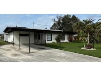 Charming single-story home with a carport and well-maintained front yard and lush tropical landscaping at 201 Ravenna N St, Nokomis, FL 34275