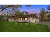 Charming single-story home featuring a well-manicured lawn, attached garage, and a basketball hoop on the driveway at 32589 Greenwood Loop, Wesley Chapel, FL 33545