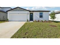 Exterior showcasing a white one-story house with a green lawn, driveway, and blue sky at 31632 Malbec Dr, Brooksville, FL 34602