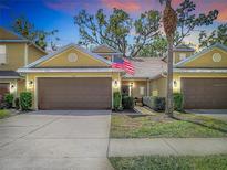Charming townhome with two-car garage, manicured lawn, and an American flag at 8539 Sandpiper Ridge Ave, Tampa, FL 33647