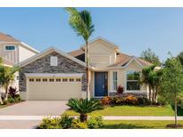 Beautiful single-Gathering home with a two-car garage, stone accents, and a well-manicured lawn with a blue entry door at 1011 Signet, Apollo Beach, FL 33572