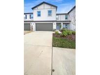 Charming two-story townhouse featuring a one-car garage, light gray facade and manicured landscaping at 32100 Pop Ash Pl, San Antonio, FL 33576