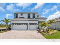 Beautiful two-story home featuring a spacious three-car garage, paver driveway, and lush landscaping at 1067 Signet, Apollo Beach, FL 33572