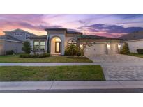 Elegant home featuring manicured landscaping, a three car garage and a stylish front door at 5516 Madrigal Way, Apollo Beach, FL 33572