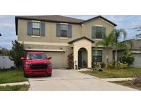 Charming two-story home with a well-maintained lawn and a driveway, accompanied by palm trees in the front yard at 14825 Crescent Rock Dr, Wimauma, FL 33598