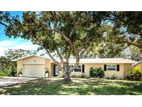Charming one-story home with mature tree, manicured lawn, and neutral exterior paint at 1825 Alberta Dr, Clearwater, FL 33756