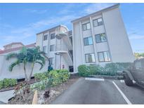 Exterior of a multi-story condominium building with a staircase and lush landscaping around the property at 557 Pinellas Bayway S # 111, St Petersburg, FL 33715