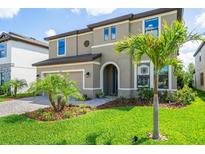 Charming two-story home with well-manicured lawn, lush landscaping, and a paver driveway leading to a two-car garage at 12654 Oak Hill Way, Parrish, FL 34219