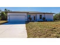 Charming single-story home featuring a two-car garage, manicured lawn, and a light and bright facade at 13089 Xavier Ave, Port Charlotte, FL 33981