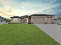 Charming single-story home featuring a well-manicured lawn and three-car garage at 15741 Autry Cir, Port Charlotte, FL 33981