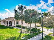 Beautiful exterior showcasing the home's lush lawn, palm trees and barrel tile roof at 4949 Sandy Glen Way, Wimauma, FL 33598