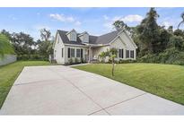 Charming home featuring a concrete driveway, lush lawn, and inviting front porch, surrounded by mature trees at 5658 Babroff Ter, North Port, FL 34291