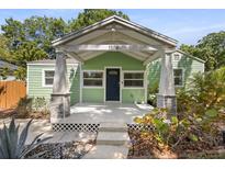Inviting covered front porch with stone accents and green siding, perfect for relaxing outdoors at 1206 E Hamilton Ave, Tampa, FL 33604