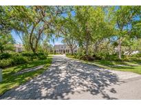 Scenic shot of a home with a long, brick-paved driveway surrounded by mature trees and lush landscaping at 1570 Oakford Rd, Sarasota, FL 34240