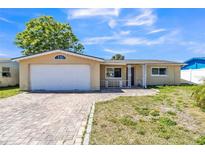 Charming single-story home featuring an attached garage, brick driveway, and a well-maintained front lawn at 10105 Vineyard Ln, Port Richey, FL 34668