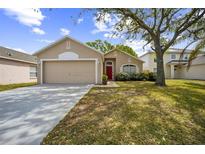 Charming one-story home featuring a red front door, attached garage, and a well-maintained lawn at 13004 Waterbourne Dr, Gibsonton, FL 33534