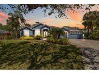 Charming blue home with manicured lawn, lush landscaping and a brick driveway at sunset at 13136 Peregrin Cir, Bradenton, FL 34212