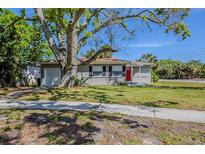 Charming single-story home with a red door and lush green lawn in a quiet neighborhood at 3645 6Th S St, St Petersburg, FL 33705