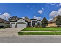 Charming home featuring a manicured front yard, a three car garage and a decorative front door at 691 Challice Dr, Spring Hill, FL 34609