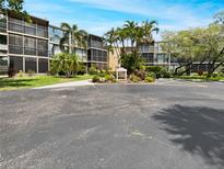 Exterior view of the condo building showcasing landscaping, palm trees, and well-maintained grounds at 612 Bird Bay S Dr # 113, Venice, FL 34285