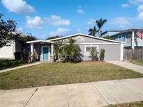 Charming single-story home with a well-maintained lawn, cute landscaping, and a bright blue front door at 141 81St N Ave, St Petersburg, FL 33702