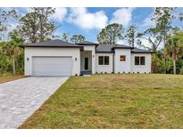 Beautiful white single-story home with a gray driveway and well-manicured lawn under a bright blue sky at 18399 Hillsborough Blvd, Port Charlotte, FL 33954