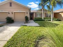 Charming home featuring a lush lawn, palm trees, and a two-car garage at 11535 52Nd E Ct, Parrish, FL 34219