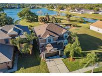 Lovely two-story home features a manicured lawn, mature palms, and stunning lake views at 31028 Baclan Dr, Wesley Chapel, FL 33545