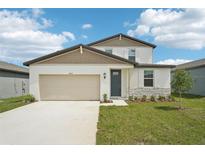 Charming two-story home featuring a 2-car garage, stone accents, and a well-manicured lawn at 31653 Wild Grape Ln, Brooksville, FL 34602