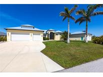Beautiful home with a three-car garage, metal roof, and lush landscaping featuring palm trees under a bright blue sky at 3215 Peace River Dr, Punta Gorda, FL 33983