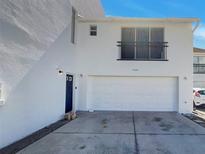 Modern two-story home featuring a two-car garage and balcony; freshly painted white with a blue front door at 9509 Citrus Glen Pl # 11, Tampa, FL 33618