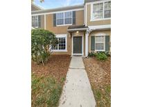 Charming tan two-story townhome with a well-manicured lawn and a welcoming entryway at 1238 Standridge Dr, Wesley Chapel, FL 33543