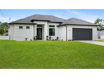A modern home with white stucco, a gray roof, a dark garage door, and a green lawn at 2805 Anniston Rd, North Port, FL 34288