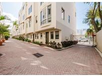 A multi-story townhome with light colored exterior, brick paved parking, and black wrought iron gate at 235 Cocoanut Ave # 129E, Sarasota, FL 34236