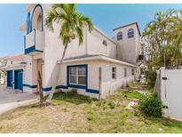 Two-story home with stucco siding, blue trim, two-car garage, and a palm tree in the front yard at 11120 5Th E St, Treasure Island, FL 33706