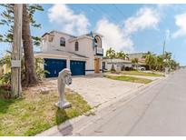 Two-story home with blue garage doors, balconies, dolphin statue, and concrete driveway at 11120 5Th E St, Treasure Island, FL 33706