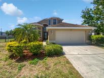 Charming home featuring a well-manicured lawn, lush landscaping, and a two-car garage at 4249 Hawksley Pl, Wesley Chapel, FL 33545