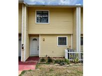 Two-story townhome with yellow siding, white trim, and a cozy front entrance at 22620 Gage Loop # 25, Land O Lakes, FL 34639