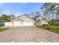 Charming single-story home featuring a brick driveway, three-car garage and lush landscaping at 2444 Grandfather Mtn, Spring Hill, FL 34606