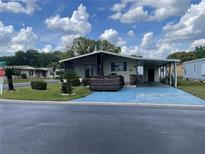 Charming single-story home featuring a covered carport and a screened-in porch, set amidst lush landscaping at 34315 Timberland Blvd, Wesley Chapel, FL 33543