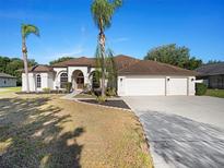 Beautiful single-story home with a three car garage, arched entry, palm trees, and well-manicured landscaping at 12402 Creek Edge Dr, Riverview, FL 33579