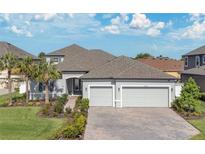 Charming single-Gathering home featuring a three-car garage, brick driveway, and manicured landscaping at 32554 Silvercreek Way, Wesley Chapel, FL 33545