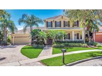 Beautiful two-story home with a well-manicured lawn, front porch, attached garage and tropical landscaping at 5405 Merritt Island Dr, Apollo Beach, FL 33572