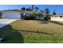 Charming single-story home with well-maintained landscaping and a two-car garage, showcasing curb appeal at 89 Mark Twain Ln, Rotonda West, FL 33947