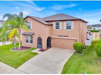 Charming two-story home with a well-maintained lawn, tall palm tree and attached two car garage at 10607 Standing Stone Drive, Wimauma, FL 33598