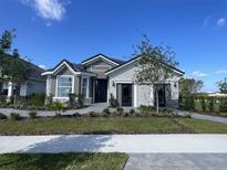 Charming single-story home featuring stone accents, gray siding, manicured landscaping, and a welcoming entrance at 2718 Wise River Lane, Zephyrhills, FL 33539