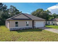 New construction single-Gathering home with a two-car garage, stone accents and a well-manicured lawn at 80 Sequoyah Dr, Port Charlotte, FL 33954