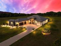 Elegant home with a spacious driveway and well-manicured landscaping, set against a colorful sunset backdrop at 6306 Foxbrook Trl, Parrish, FL 34219